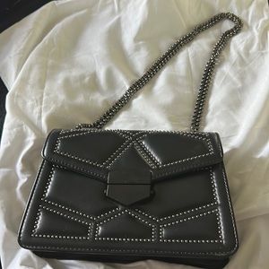 Black stuffed bag with adjustable strap and metal closure